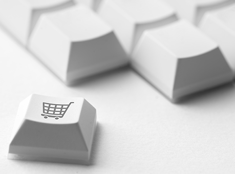 Weiße Tastatur mit einer herausgebrochenen Taste, auf der ein Einkaufswagen-Symbol abgebildet ist – Symbol für Online-Shopping oder digitale Einkaufsprozesse.
